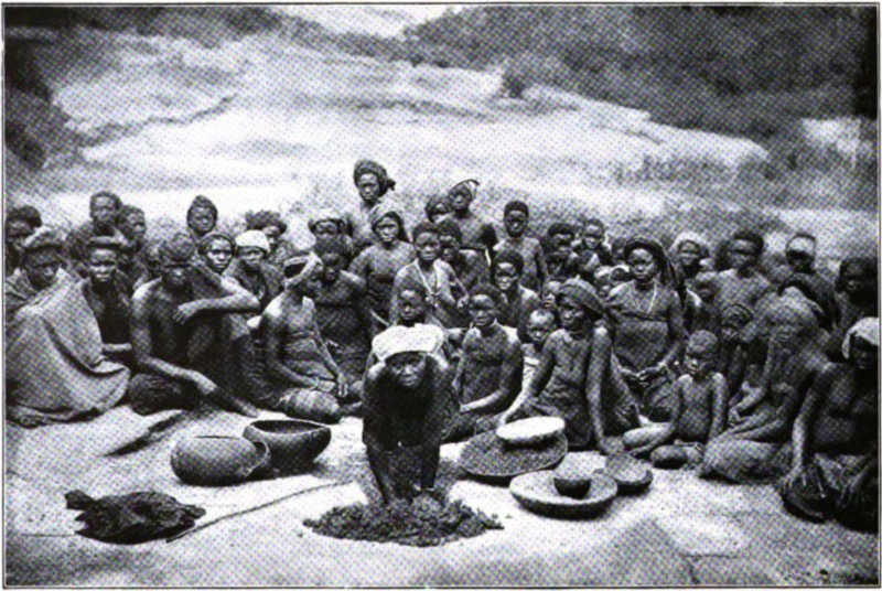 Grupa przedstawicieli ludu Yoruba z Mount Ado w Nigerii, siedzących lub stojących w tradycyjnych strojach. Ilustracja z około 1900 roku, z publikacji kolonialnej Mockler-Ferrymana.