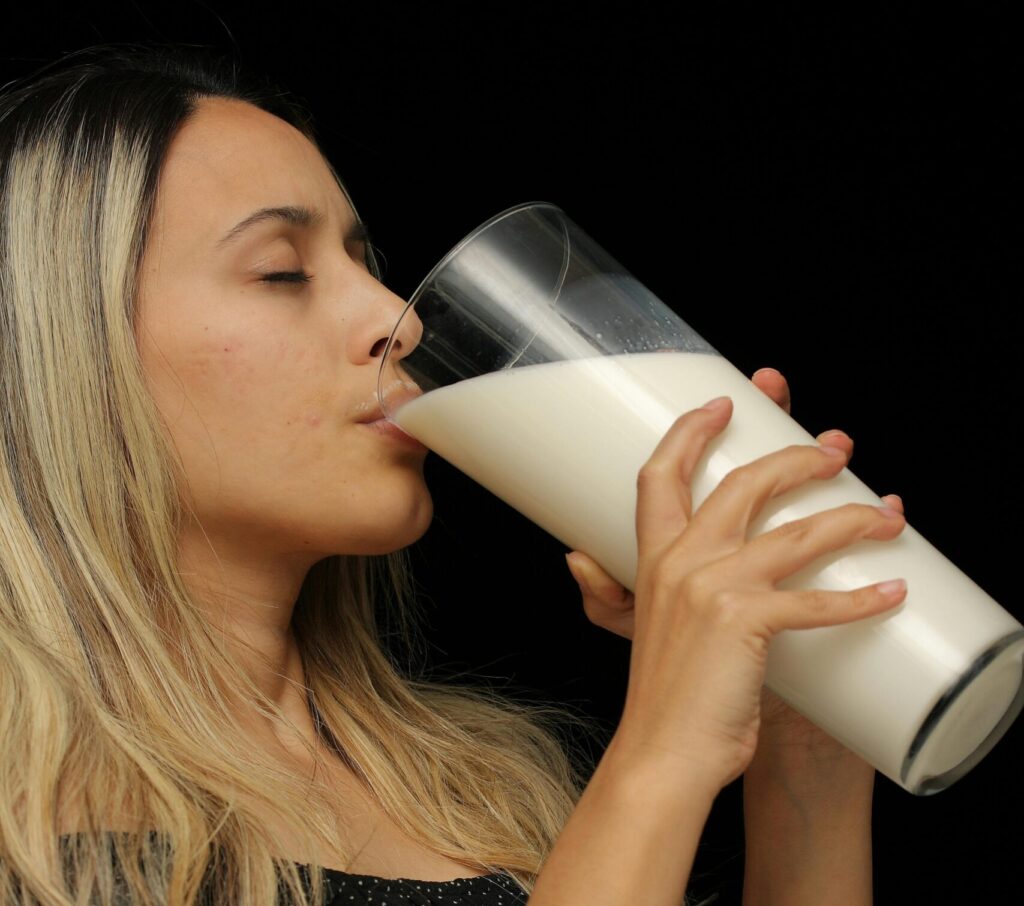 Kobieta pijąca mleko, ilustracja przedstawiająca działanie genu laktazy odpowiedzialnego za trawienie laktozy u dorosłych ludzi.